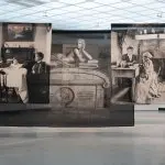 Installation view of three photographs printed on fabric that hang from the museum ceiling and overlap each other.