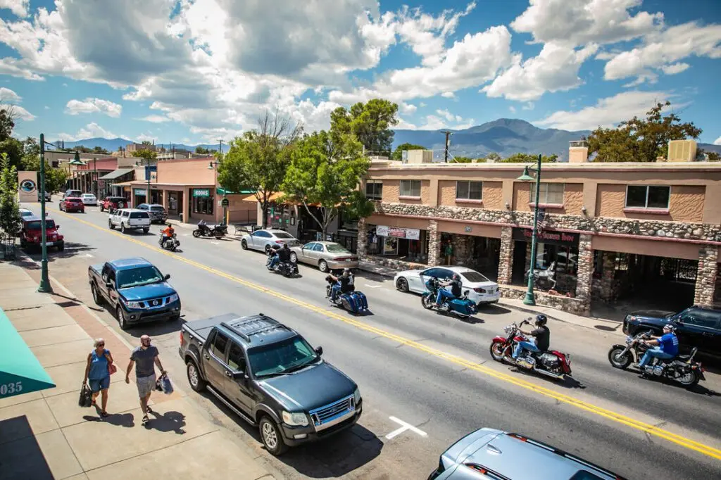 Motorcycles and cars going down Main Street in Cottonwood. People are walking on the sidewalk.