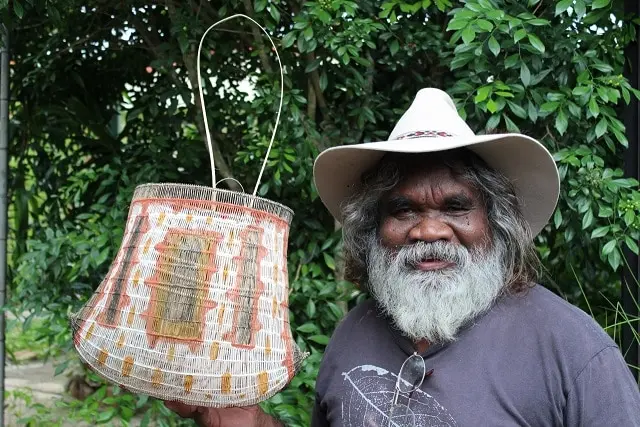 Abe stands in a hat with his woven basket