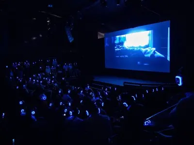 People watch a film screen with headphones that are illuminated. 