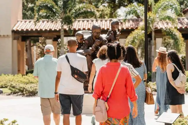 A group of people view the Fred Rogers statue at Rollins College.