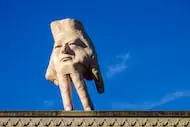 A 16-foot-tall hand sculpture named Quasi stands perched on its fingertips atop the roof of...