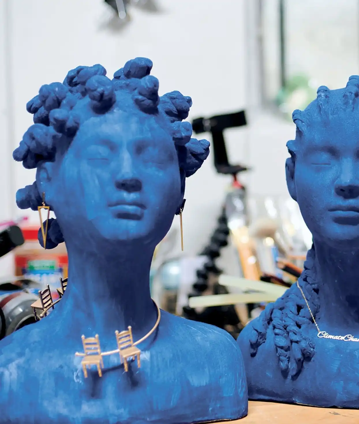 two blue busts, one with a gold necklace featuring two chairs