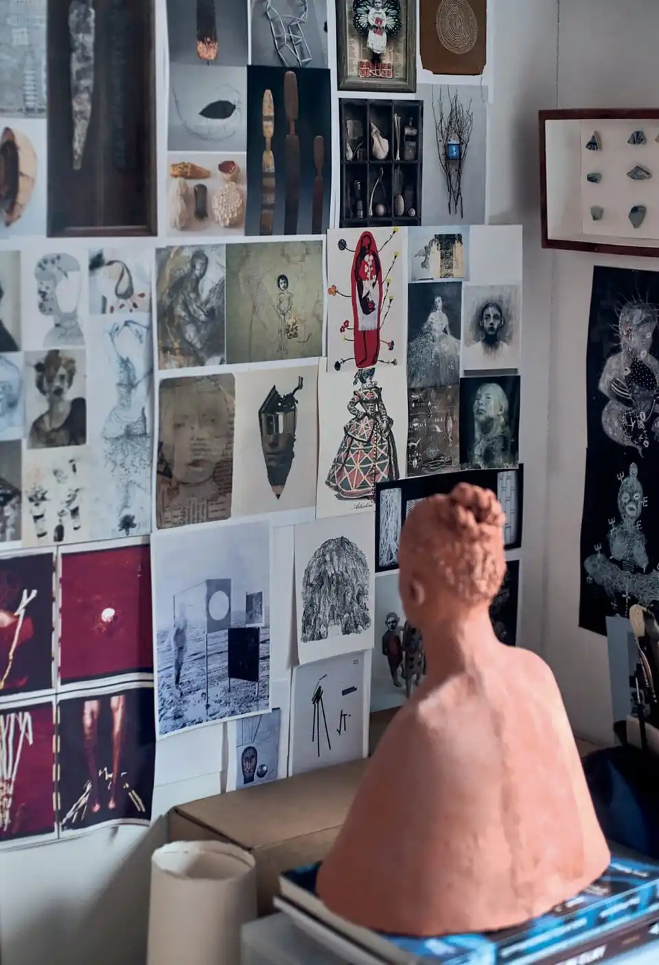 a ceramic bust rests on a table and faces a wall of various works