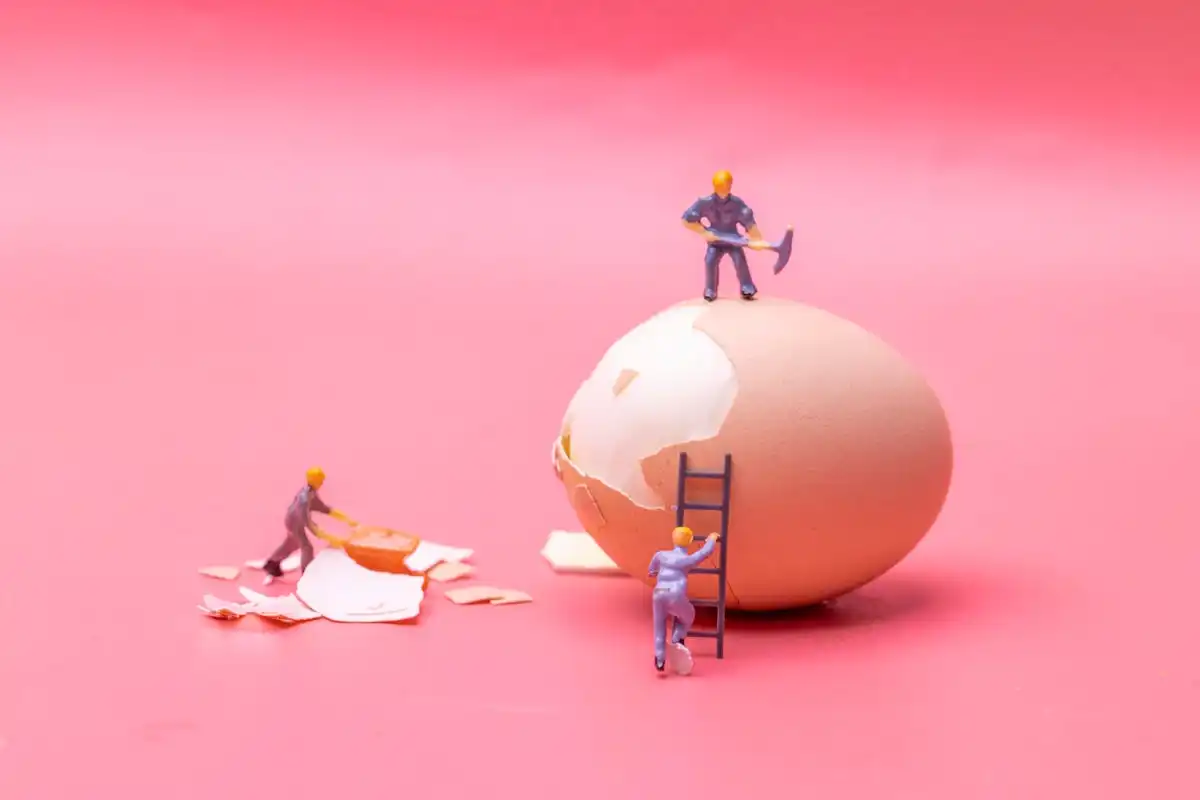 Three figurine men working on an egg