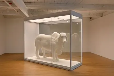 A life-size butter sculpture of a cow in a vitrine. 