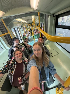 A person takes a selfie with several others while standing on a train.