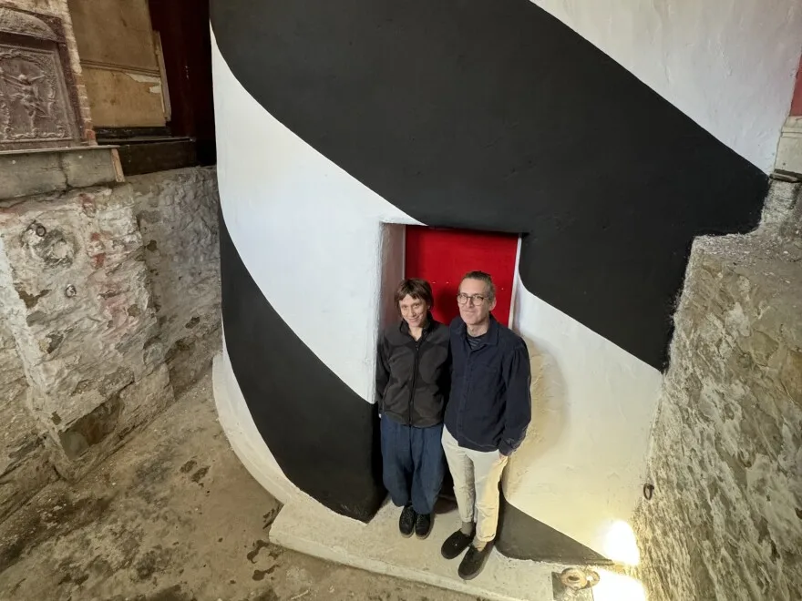 Lenka Clayton and Phillip Andrew Lewis stand next to the base of their working lighthouse, built within a Pittsburgh row house.