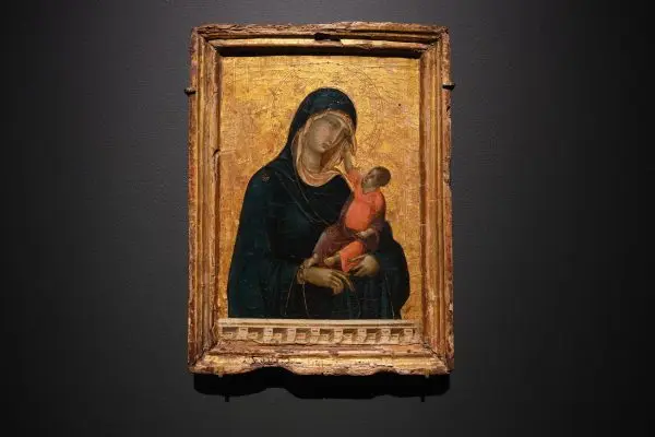 A worn painted portrait of The Virgin Mary holding an infant Jesus on a shiny gold background.