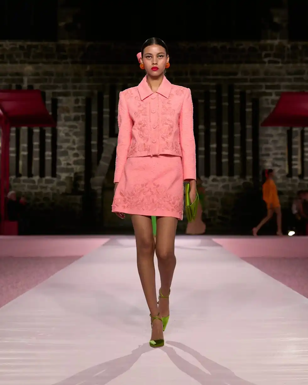 model walking on a runway in a pink outfit