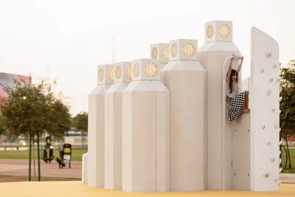 a child swings from a beige architectural structure