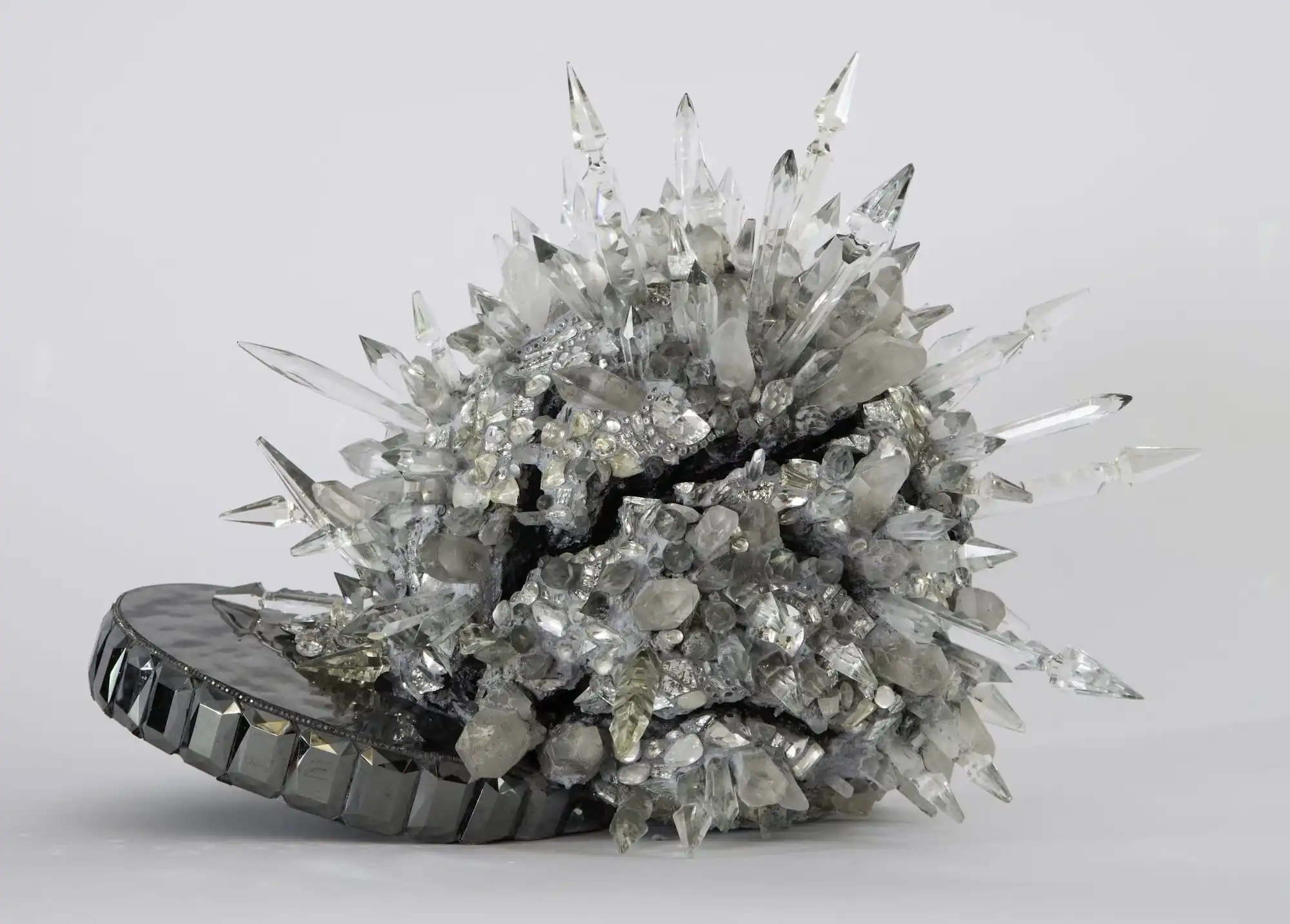 an abstract sculpture of an orb covered in crystals, attached to a disk