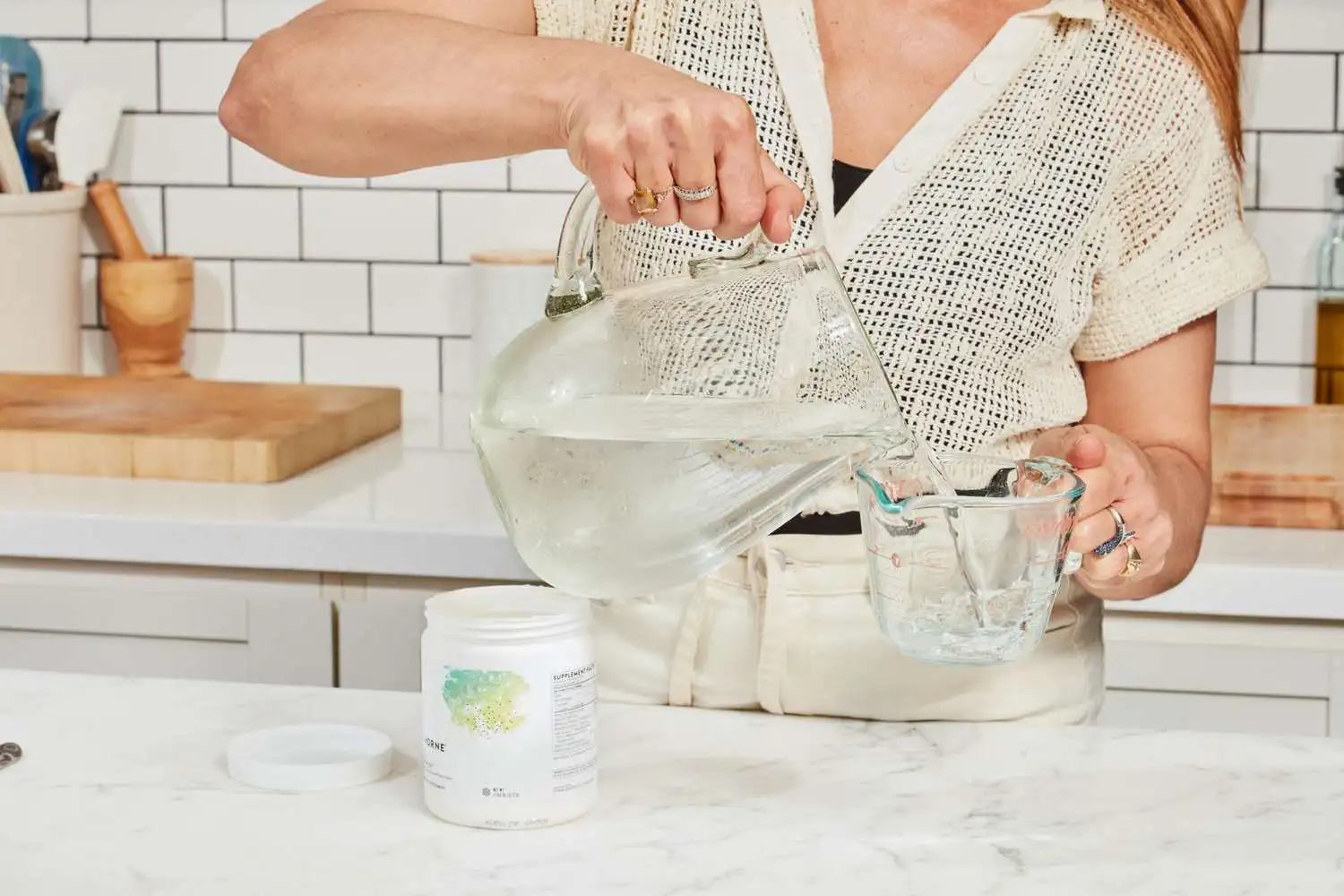 A person pouring water into a measuring cup to use with the Thorne Research Catalyte