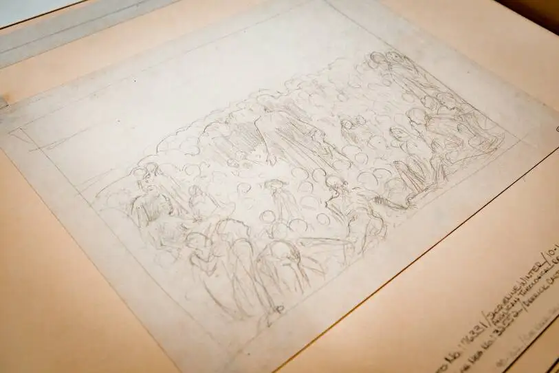 A pale, rectangle paper has a faint sketch of a central human surrounded by loose frames of other figures. 