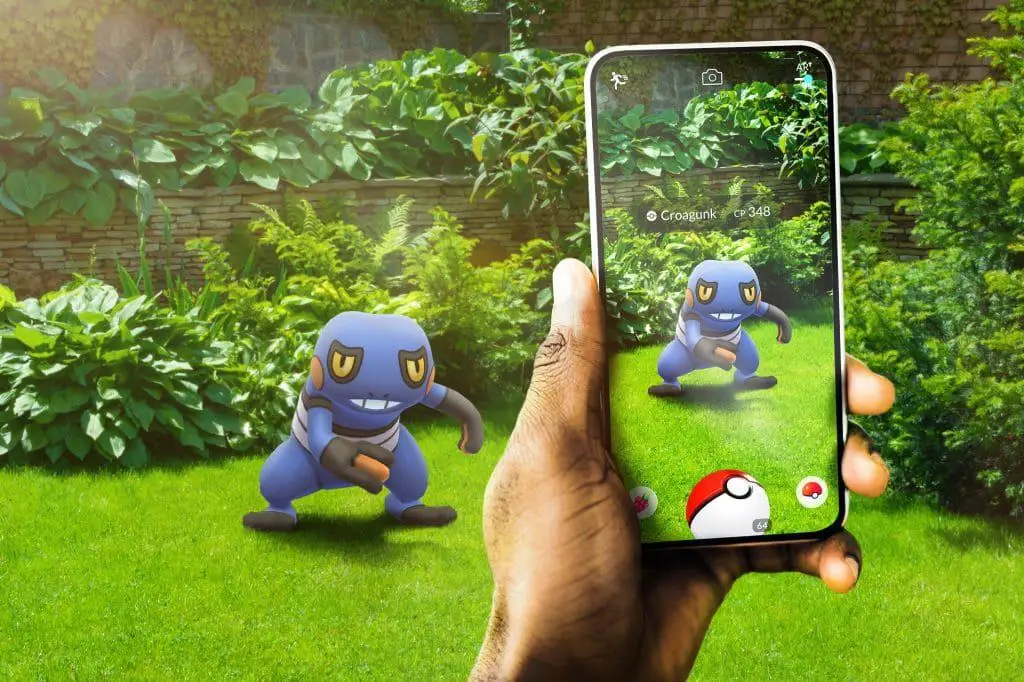 Imagem promocional de Pokémon Go mostra smartphone exibindo imagem do pokémon Croagunk em realidade aumentada.