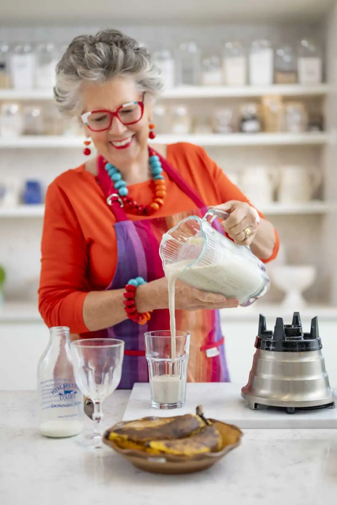 Prue Leith makes a smoothie using overripe bananas — skin and all. (She does cut off the tip and tail.) She pours smoothie from the blender into a glass, with overripe bananas in the foreground. 