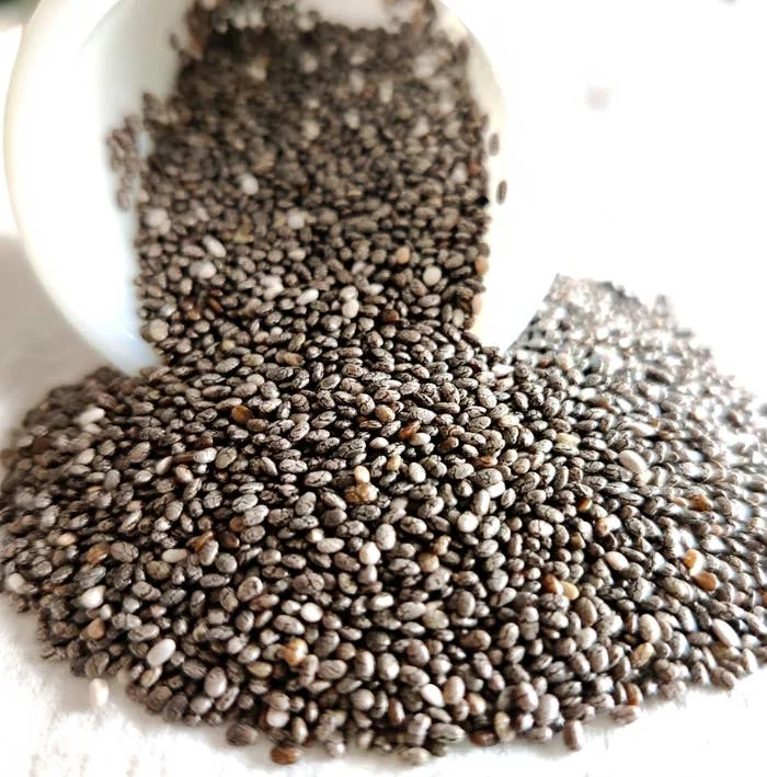 Chia seeds spilling from a white container onto a white surface