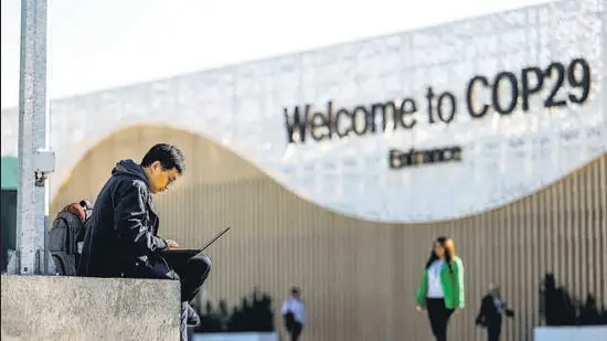 A man uses his laptop as he sits near the COP29 United Nations climate change conference pavilion, in Baku, Azerbaijan, on Friday. (REUTERS)