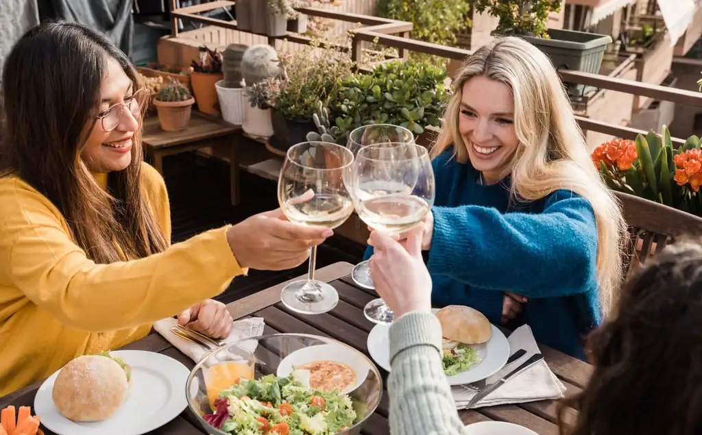 Women drinking wine accompanied by a salad. According to research, beer drinkers have lower-quality diets than wine drinkers, possibly in part because wine is often paired with healthier meals. Photo: Shutterstock