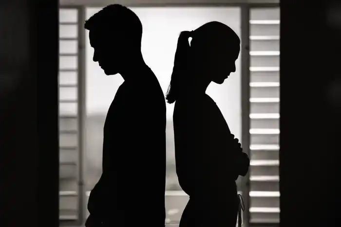 Silhouette image of man and woman standing back-to-back in window