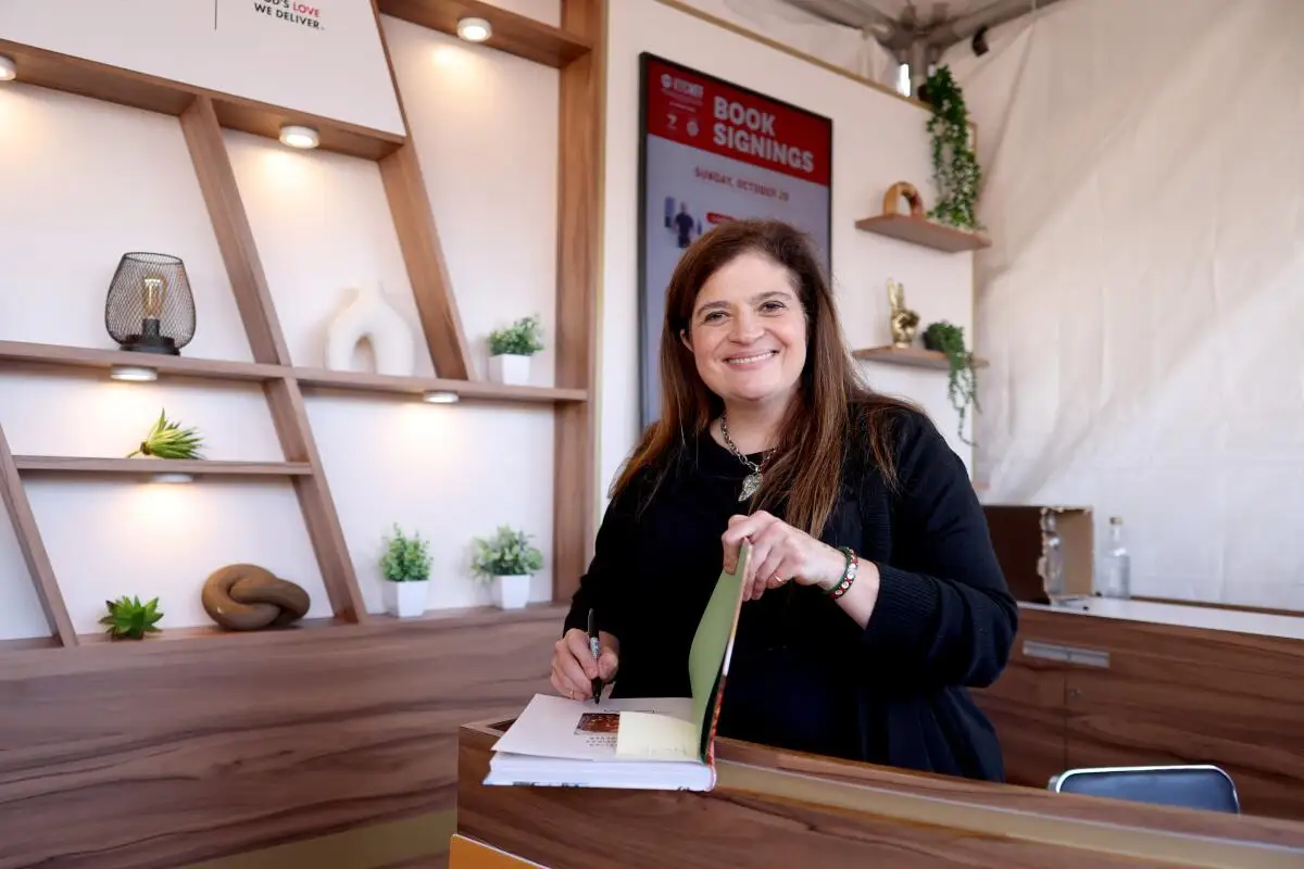 Alex Guarnaschelli signing a large book.