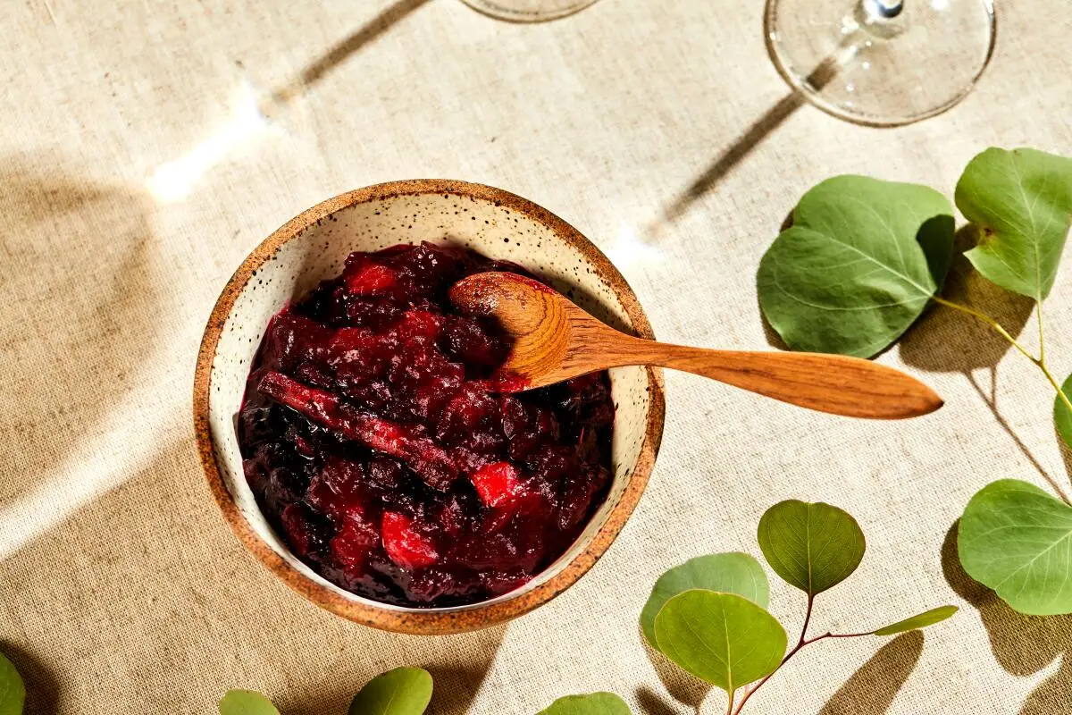 A bowl of citrus cranberry sauce, a wooden spoon resting in it