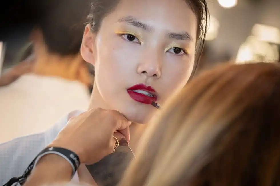 model backstage at fashion week applying lipstick