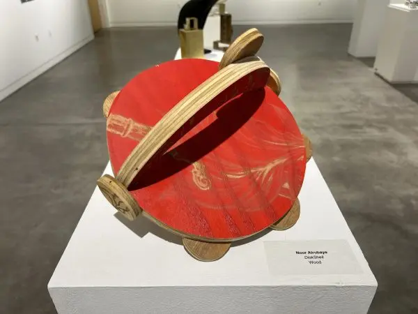 A wooden disk art piece on display.