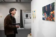 Brian Jin of Carrollton pauses in front of Amy Mu’s “cut / uncut,” 2024, acrylic, during the...