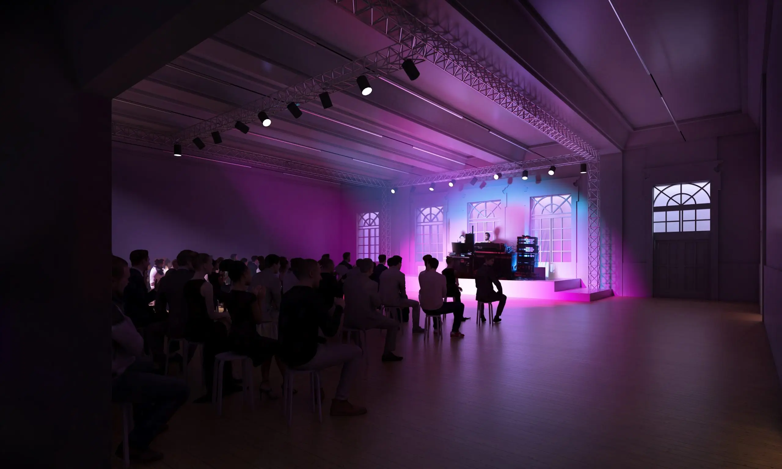 A dimly lit concert hall with an audience seated in front of a stage with pink and blue lighting.