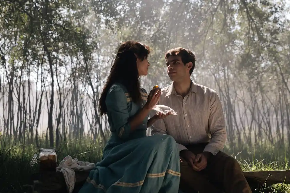 two people sitting in a forested area sharing food