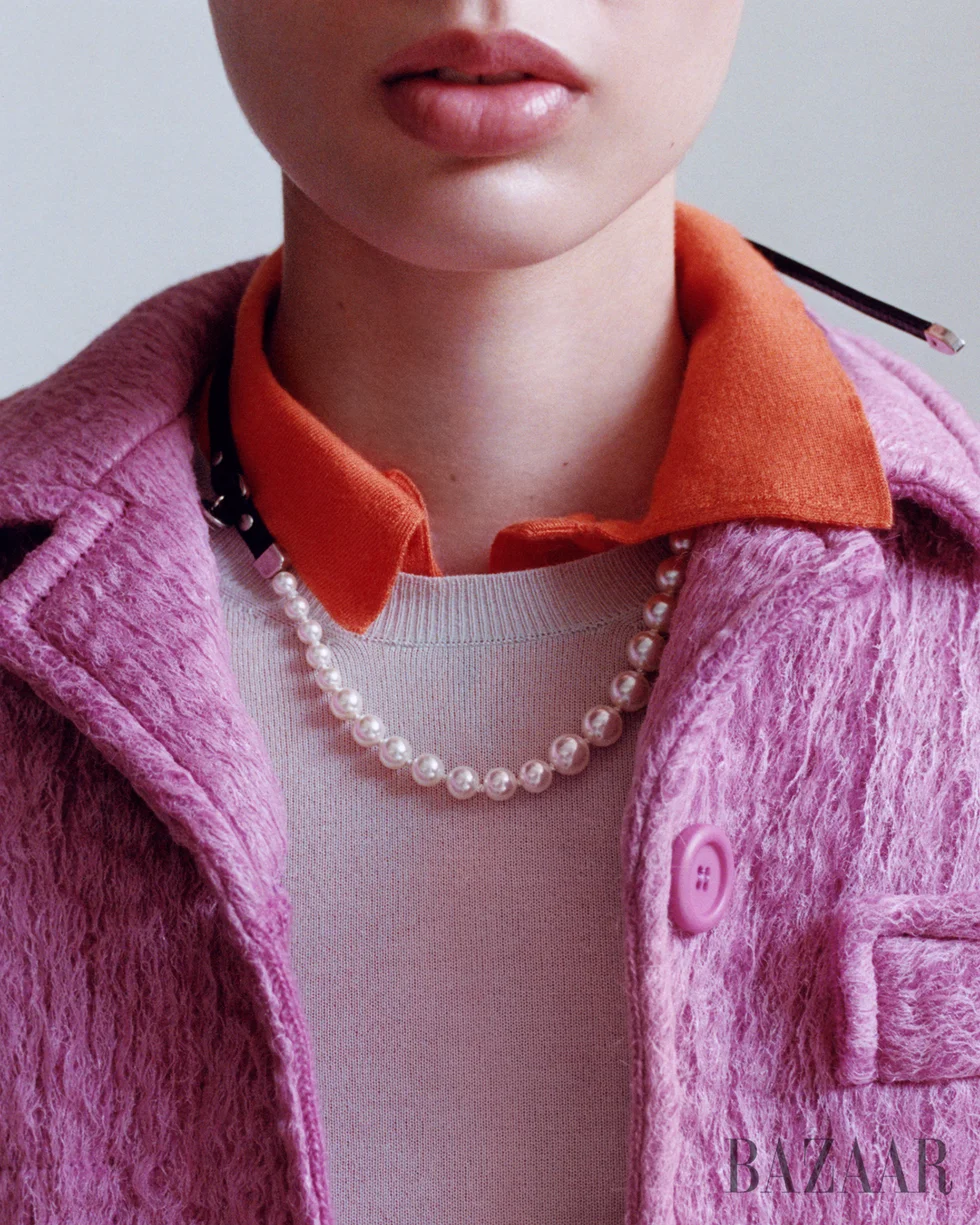 Closeup of a young woman wearing a pink jacket and pearl necklace