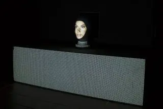 A face projected on a black wall