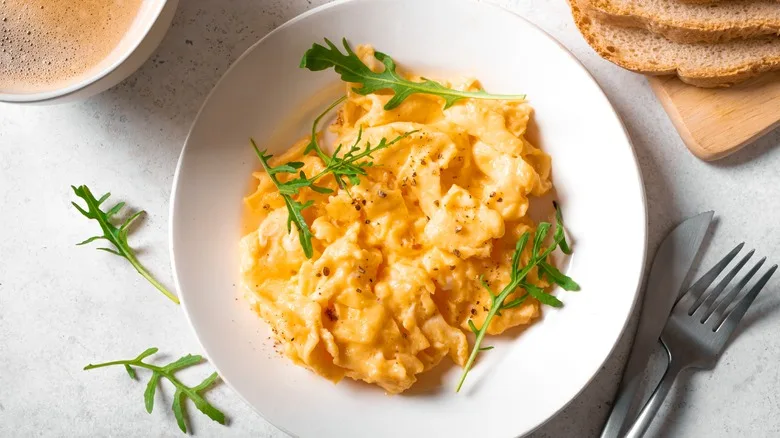 fluffy scrambled eggs on a plate with arugula