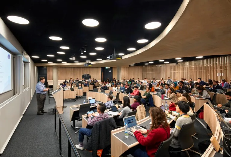 A general view of a teacher leading a class in a curved lecture hall