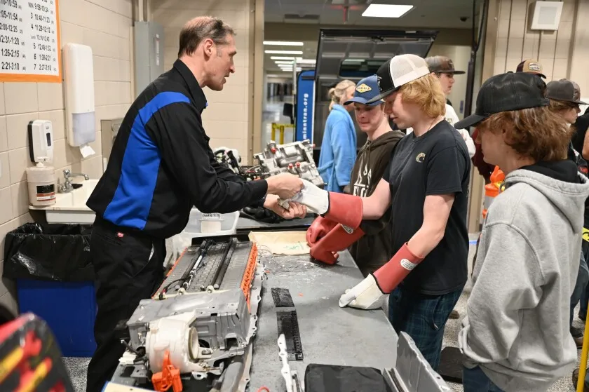 A man helping a student with their glove.