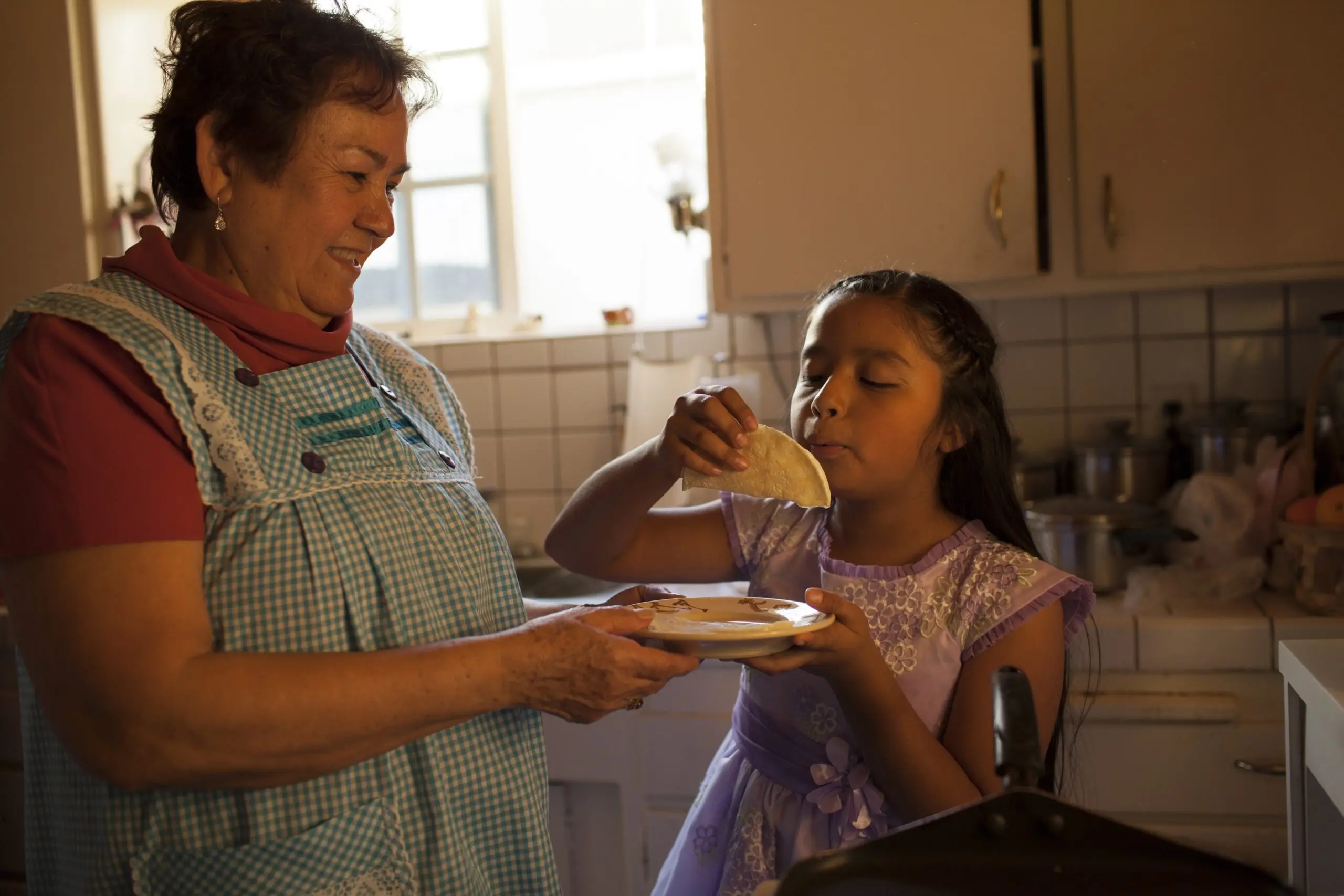 Hispanic woman cooking for granddaughter in kitchen - stock photo