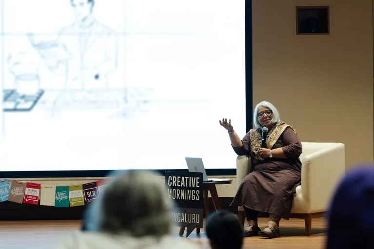 Shobhana Narasimhan talks into a mic while seated on stage