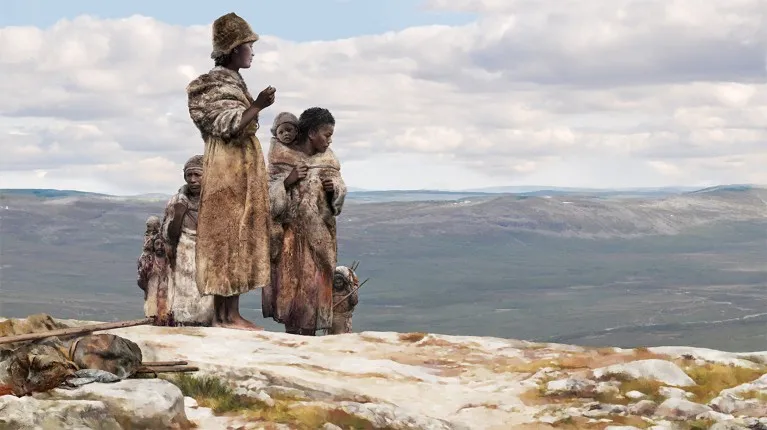 People dressed in furs, walking on a steppe with moors and hills in the distance.