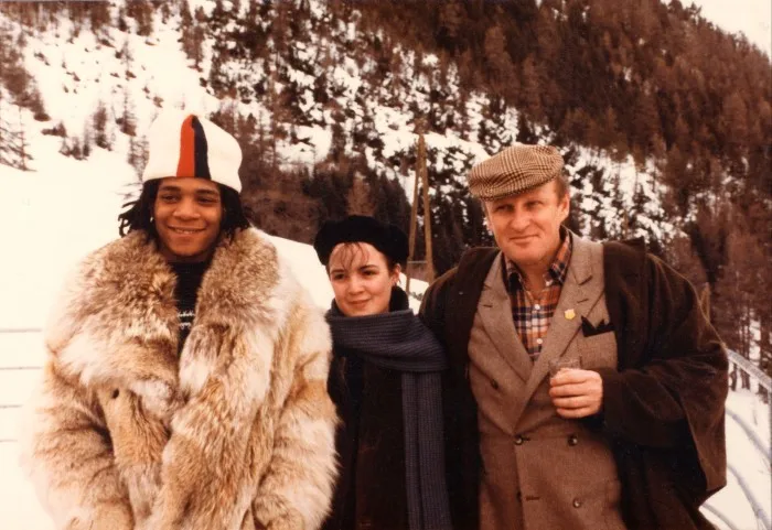 Three people pose for a holiday photograph against the backdrop of a snowy mountainside ski resort