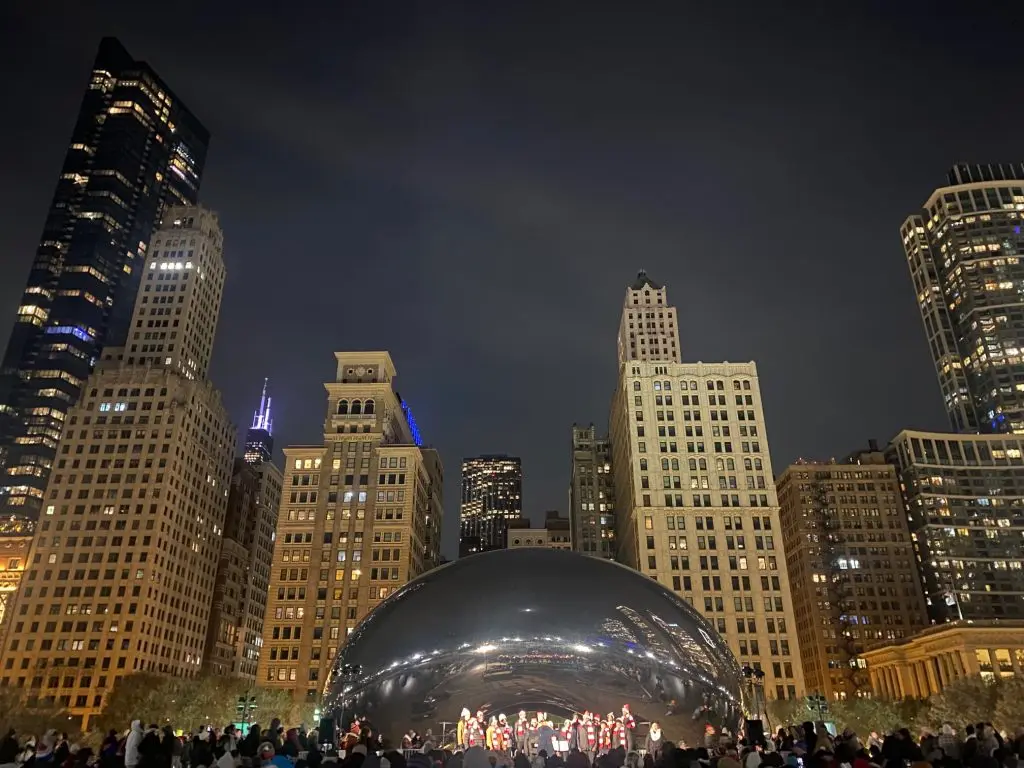 Photo of The Bean in front of Chicago skyline at night.