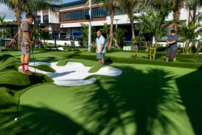 Jason Vazquez, Jr., 11, left, Jason Vasquez and Silas Vazquez, 10, play golf at PopStroke on December 20, 2024, in West Palm Beach, Florida. Tiger Woods, Greg Bartoliand TaylorMade Golf Company are the owners.