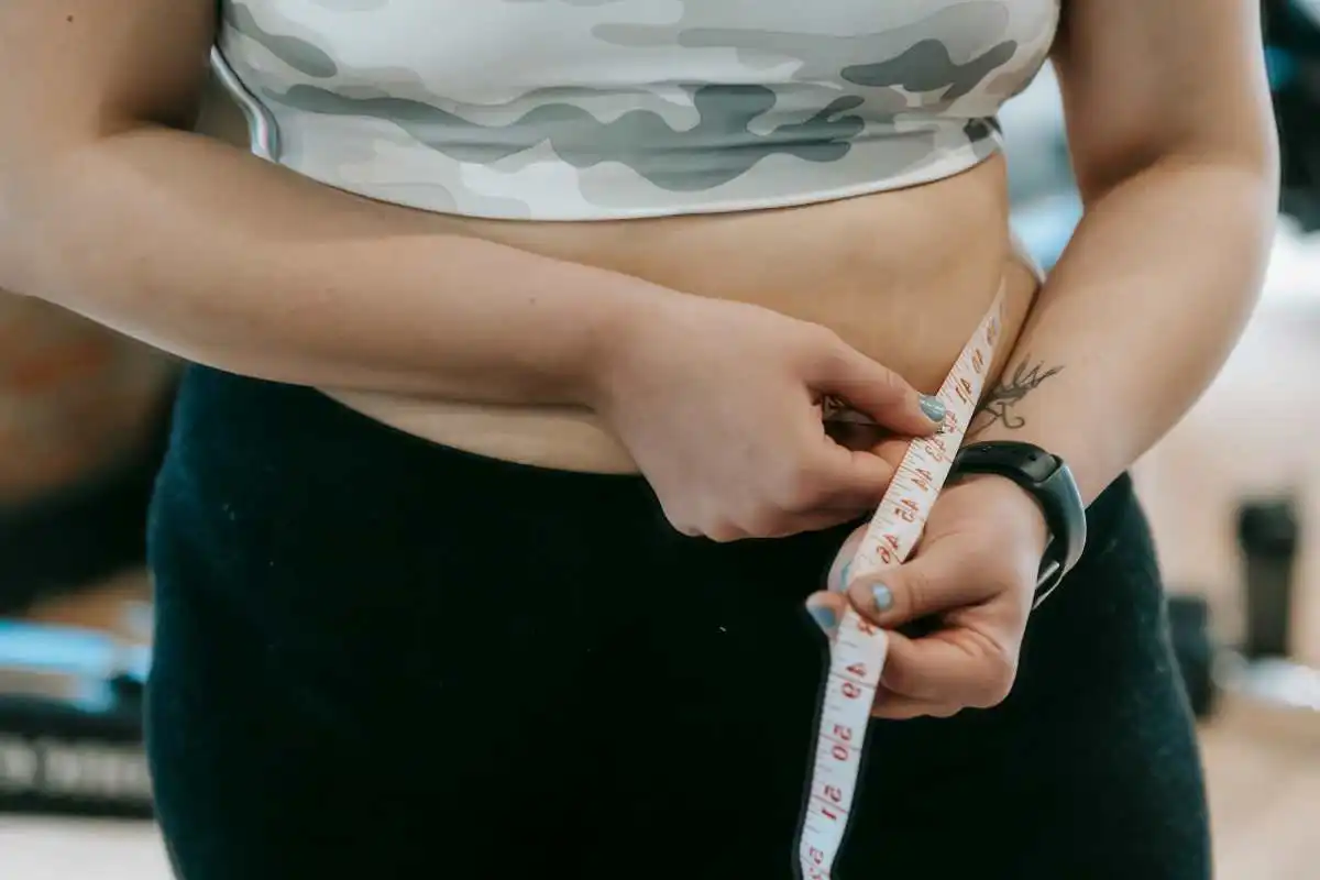 A woman measuring her waist size during her weight loss journey  (Image Source: Pexels | Andres Ayrton)