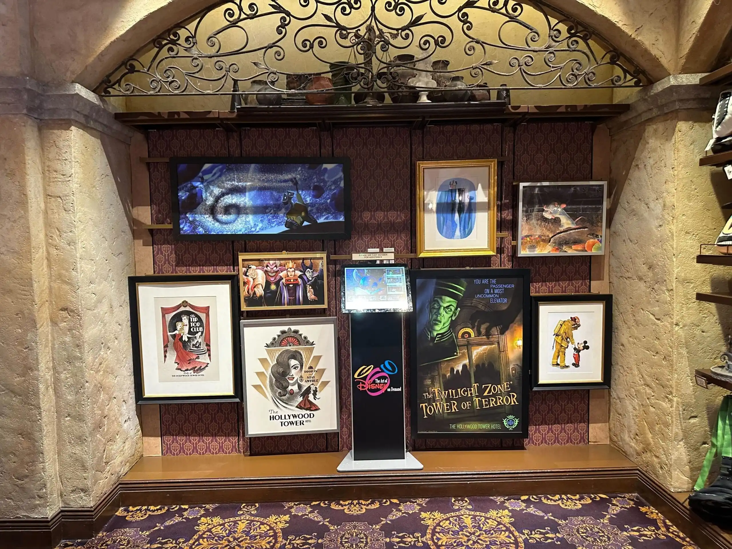 A captivating display of framed Tower of Terror themed posters and artifacts adorns a purple patterned wall, creating an artful homage to Hollywood's eerie glamour.