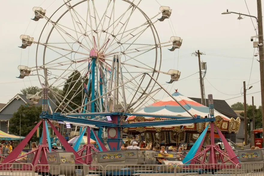 View of brightly colored carnival rides including a Ferris wheel.