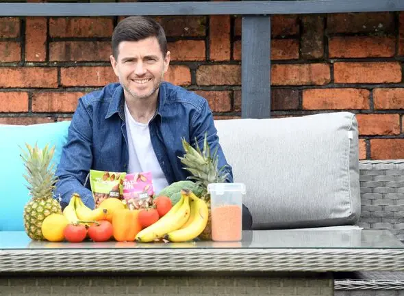 Steffan Rhys sits at an outdoor table with a selection of healthy foods