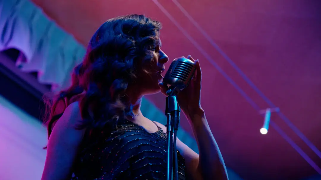 A woman singing into an old-timey microphone.