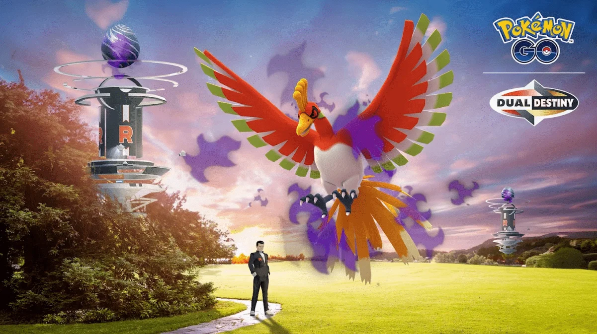 A large Shadow Ho-Oh looms over Giovanni, who is stood on a path in a green park. To the left of Giovanni are trees, and behind them a Pokémon GO gym with a Shadow Raid egg on top of it. To the right of Ho-Oh another gym is shown. Above the gym is text reading 'Pokémon GO Dual Destiny'