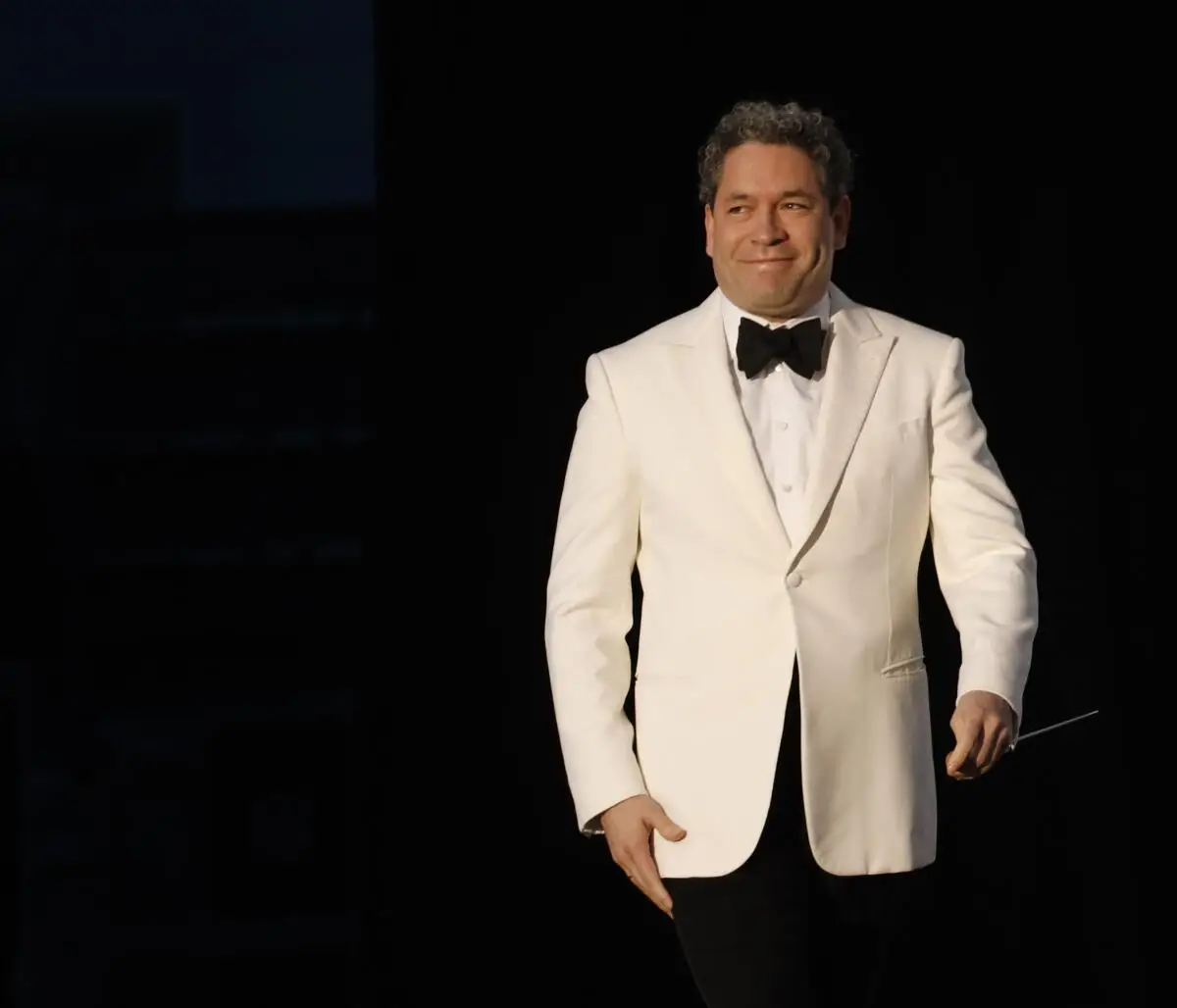 Gustavo Dudamel in a white jacket and black tie, smiling