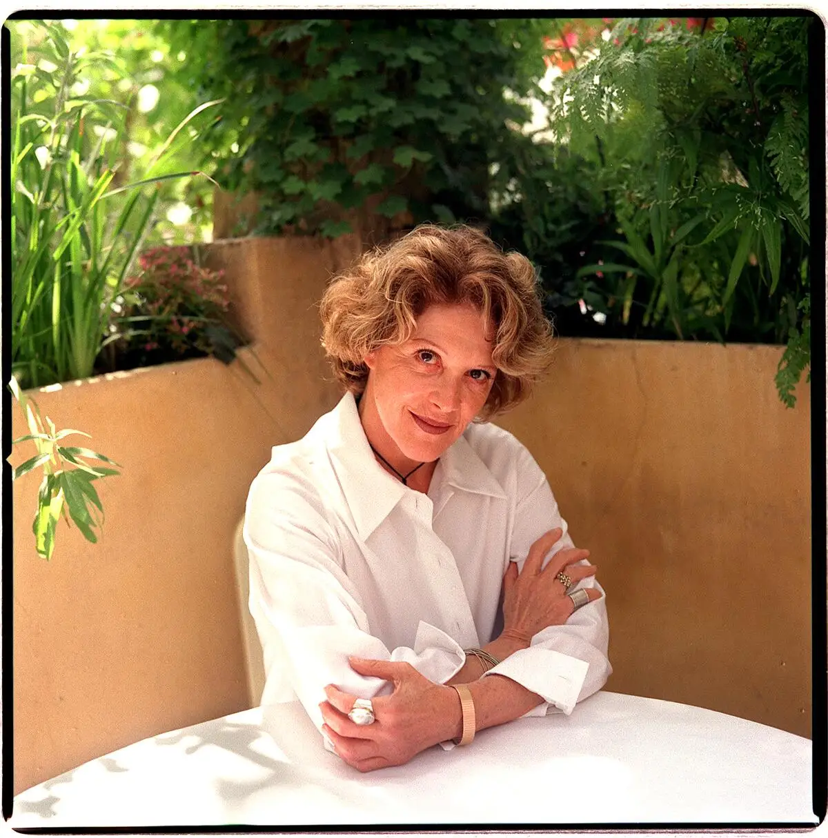 Actress Linda Lavin sits in a corner restaurant booth, arms crossed, head tilted